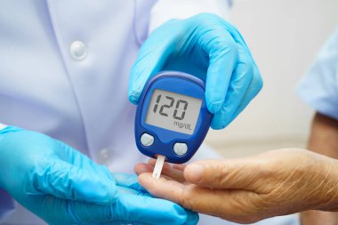 Diyabet tedavisinde kan şekeri seviyesini kontrol etmek için dijital glikoz ölçer kullanan Asyalı doktor.