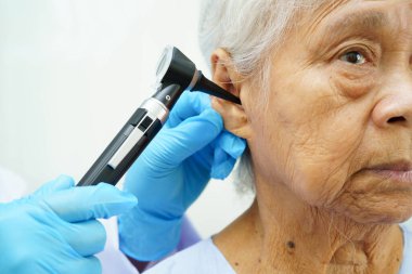 Otolaryngologist ya da ENT hekim doktoru yaşlı hasta kulağını otoskopla muayene ediyor, işitme sorunu var..