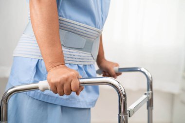 Asya baş ağrısı. Esnek destek kemeri takıp yürüteç takıyor..