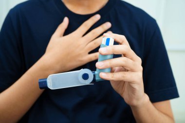 Astım ve kronik obstrüktif akciğer hastalığı KOAH, Asyalı genç ölçülü doz solunum cihazı kullanıyor..