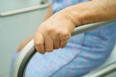 Asyalı yaşlı kadın hasta tuvalette tuvalet desteği kullanıyor..