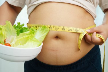 Koca göbekli, şişman, kilolu ve sağlıklı yiyecekleri olan Asyalı bir kadın..