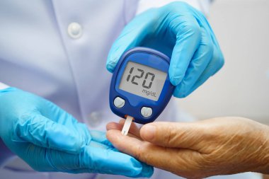 Diyabet tedavisinde kan şekeri seviyesini kontrol etmek için dijital glikoz ölçer kullanan Asyalı doktor.