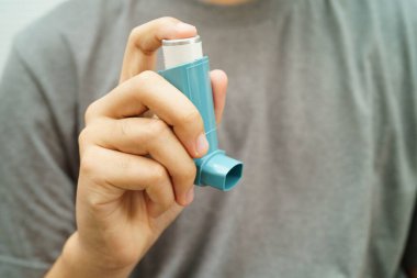 Astım ve kronik obstrüktif akciğer hastalığı KOAH, Asyalı genç ölçülü doz solunum cihazı kullanıyor..