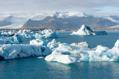 Buzdağlarıyla dolu pitoresk bir buzul gölü. Güzel gökyüzünün altında karlı dağlar.