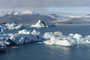 Değişen büyüklükteki buzdağları serin ve güneşli bir günde, buzul gölünde yüzer..