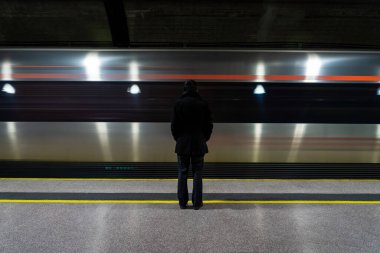 Platformda durup metro ya da tren istasyonundan geçen treni izleyen yalnız bir adam. Tren peronunda duran takım elbiseli yalnız bir işadamı.