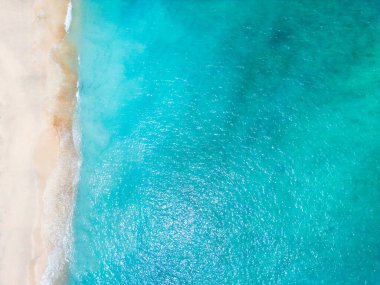 Hava aracı (yukarıdan aşağıya) deniz dalgaları ve beyaz kuma bakıyor. Turkuaz mavi su, tropikal tema. Dalgalı tropik okyanus dokusu