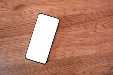 Elinde boş ekran olan akıllı telefon. Masanın üzerine yerleştirilmiş boş bir cep telefonu ekranı