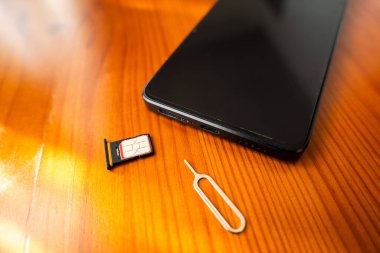 Sim Card ve Fırlatma İğnesi akıllı telefonun yanında. nano sim kart masada, yakın plan.