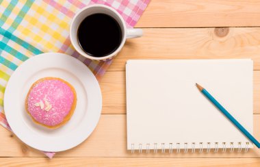 Çilekli Donut ile defter kopya alanı ile sıcak siyah kahve.