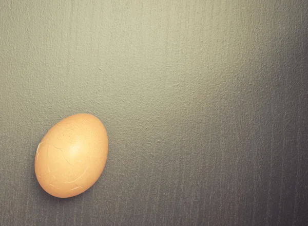 Тріснуте яйце на чорному дерев'яному тлі вінтажний тон . — стокове фото