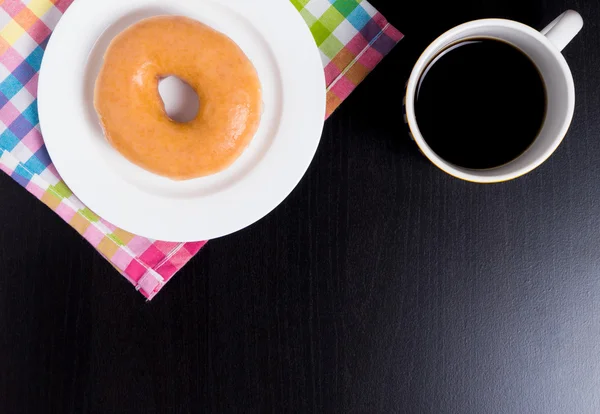 Кофе-брейк с медовым пончиком на черном столе с копировальным местом . — стоковое фото