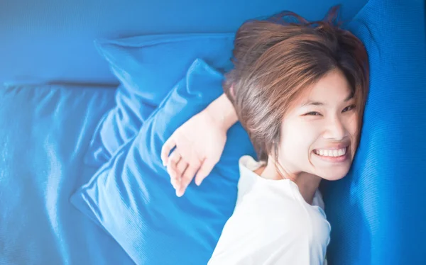 Menina japonesa feliz deitado no assento sofá azul . — Fotografia de Stock