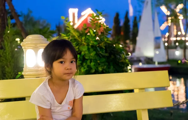 Feliz asiática bebé niña sentado en vacaciones luz parque . — Foto de Stock