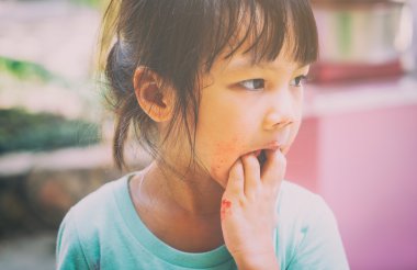 Aç yoksul Asyalı çocuk elini ona yiyecek son test için yalama.
