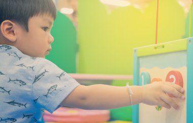 Asyalı çocuk üzerinde eğitici oyuncak oyun. Japon bebek renkli oyuncakla saymak öğrenme. Çocuklar için anaokulu sınıfı Oda pratikte öğrenme numarası.