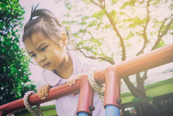 Asiático jardim de infância estudante escalando o topo do parque infantil parecendo solitário — Fotografia de Stock