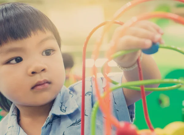 Asian children playing on educational toy. Japanese baby learning to count with colorful toy. Number learning practice in kindergarten class room for children.