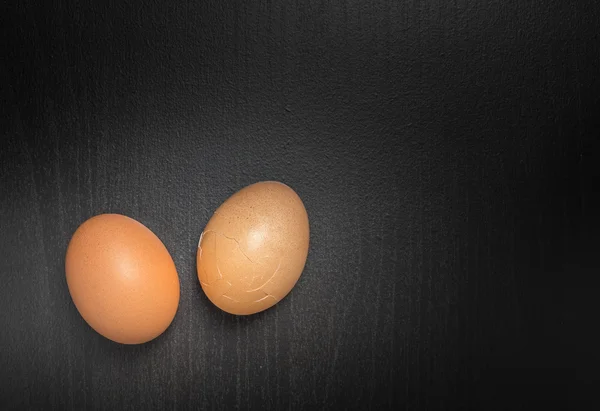 Dois ovos rachaduras no fundo preto com espaço de cópia — Fotografia de Stock