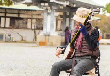  Bir müzisyen Osaka Kalesi önünde Japon geleneksel müzik çalıyor