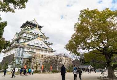 Turistler Osaka Kalesi parkta dolaşan.