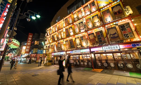 Shinseikai sokak Osaka favori gece hayatı sahne oluyor. Tsutenkaku Kulesi yer alır.