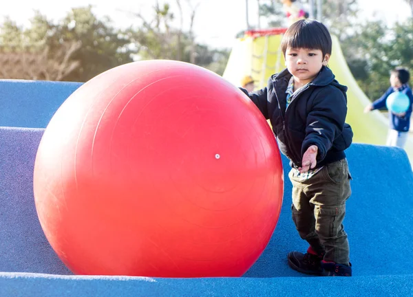 Ασιατικές αγόρι παίζει με μεγάλες λαστιχένιες μπάλα σε παιδική χαρά — Φωτογραφία Αρχείου