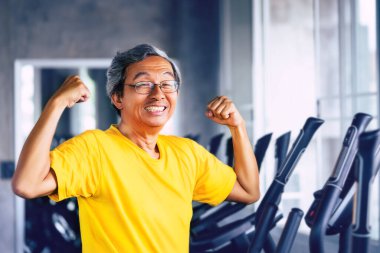 Kıdemli Asyalı Adam fitness salonunda güçlü sağlıklı yaşam konsepti için kaslarını gösteriyor..