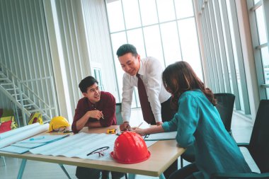 Mühendis ve mimarla Mutlu İnşaat Ekibi toplantı masasında gülüyor ve gülümsüyor..