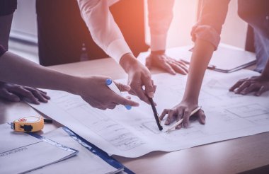 İnşaat mühendisi ve mimar inşaat planıyla birlikte çalışma masasında beyin fırtınası yapıyor.