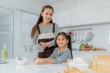 Asyalı anne ve Daugther mutfak tezgahında ön planda ekmekle birlikte fırın yapıyorlar..