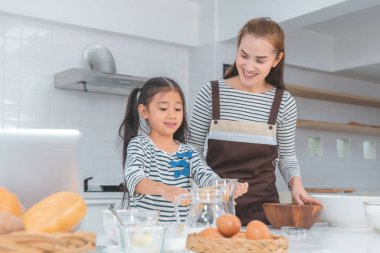 Mutlu Asyalı anne ve kızı ekmek ve fırın için ev mutfağında ebeveynlik konsepti yapıyor..