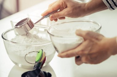 Kadın eli, fırın malzemeleri için un hazırlıyor. Cam kaseye karıştırılıyor..