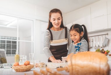 Anne ve çocuk, aile aktivitesi konsepti için ev mutfağında fırın hazırlarken eğleniyorlar..