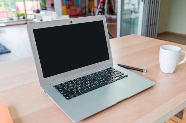 Blank Laptop screen on working table with coffee and notebook for computer application mock up for working at home.