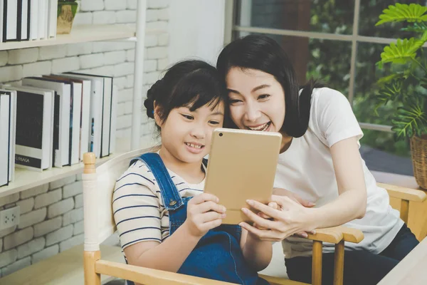 Asian mother and girl is making video call on a tablet to family during quarantine period for family connection concept.