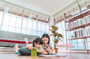 Anne ve kızı kitabı boyuyor ve aile birliği konsepti için yerde ödev yapıyor..