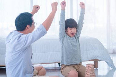 Baba ve oğul yatak odasında oyuncak bloğu oynuyorlar ve golü mutlulukla kutluyorlar.