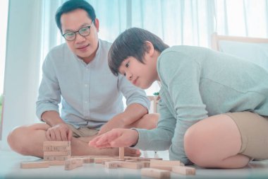 Baba, evdeki tahta oyuncak bloğu kulesiyle oynayarak oğluna aile eğitimi kavramını öğretiyor..