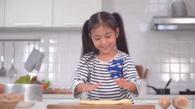 Küçük Asyalı kız pastane mutfağı için diz çöküp hamur hazırlıyor..