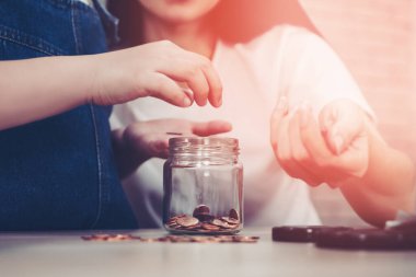 Annem para ve zenginlik eğitimi kavramı için tasarruf kavanozu ve kumbarasını kullanarak tasarruf ve planlama üzerine Daugther 'a ders veriyor..