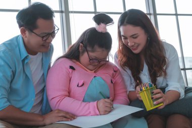 Down Syndrom çocuğuna anne ve babası tarafından eğitim amaçlı bakılıyor. pozitif otizm çocuk sağlıklı yaşam tarzı konsepti için.