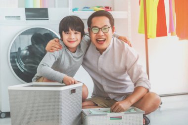 Mutlu Asyalı baba ve oğul, aile birliği konsepti için evde çamaşır yıkarken gülümsüyor ve gülüyor..