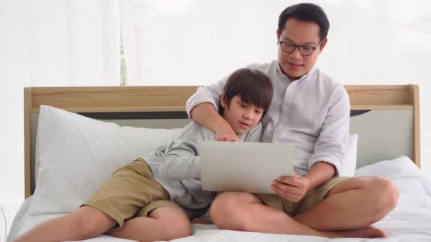Азиат Отец Учит Своего Сына Пользоваться Интернетом Ноутбуком Вместе Кровати — стоковое видео