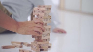 Çocuk el yapımı tahta bir oyuncak blok kulesi yüksekte ve aşağı düşüyor..