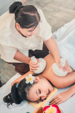 Genç Asyalı kadın otantik bir kaplıcada Tayland bitkisel topu masajı yaptırıyor.