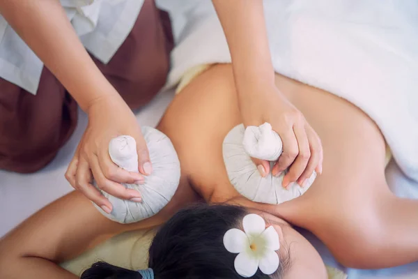 年轻的亚洲女人正在用一种真正的外科手术式温泉按摩泰式草药球热敷按摩 — 图库照片