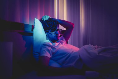 Depresyondaki uykusuzluk çeken beyaz adam gece geç saatlerde stres ve intihar konsepti için siyah haplarla başını yatakta tutuyor..