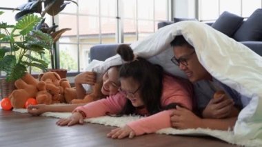 Otizmli Çocuk Ailesi, evde oturma odasında battaniye ve beraberlik konsepti altında birlikte oynuyor..